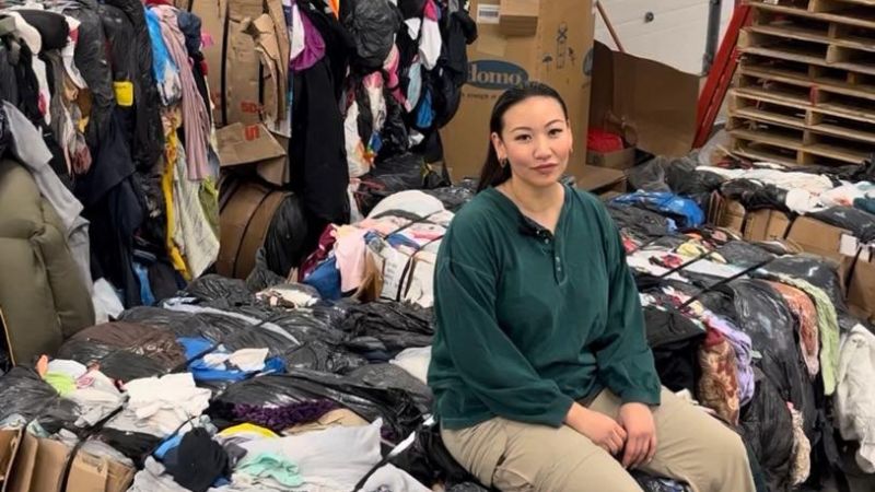 A woman sitting on a pile of clothes.